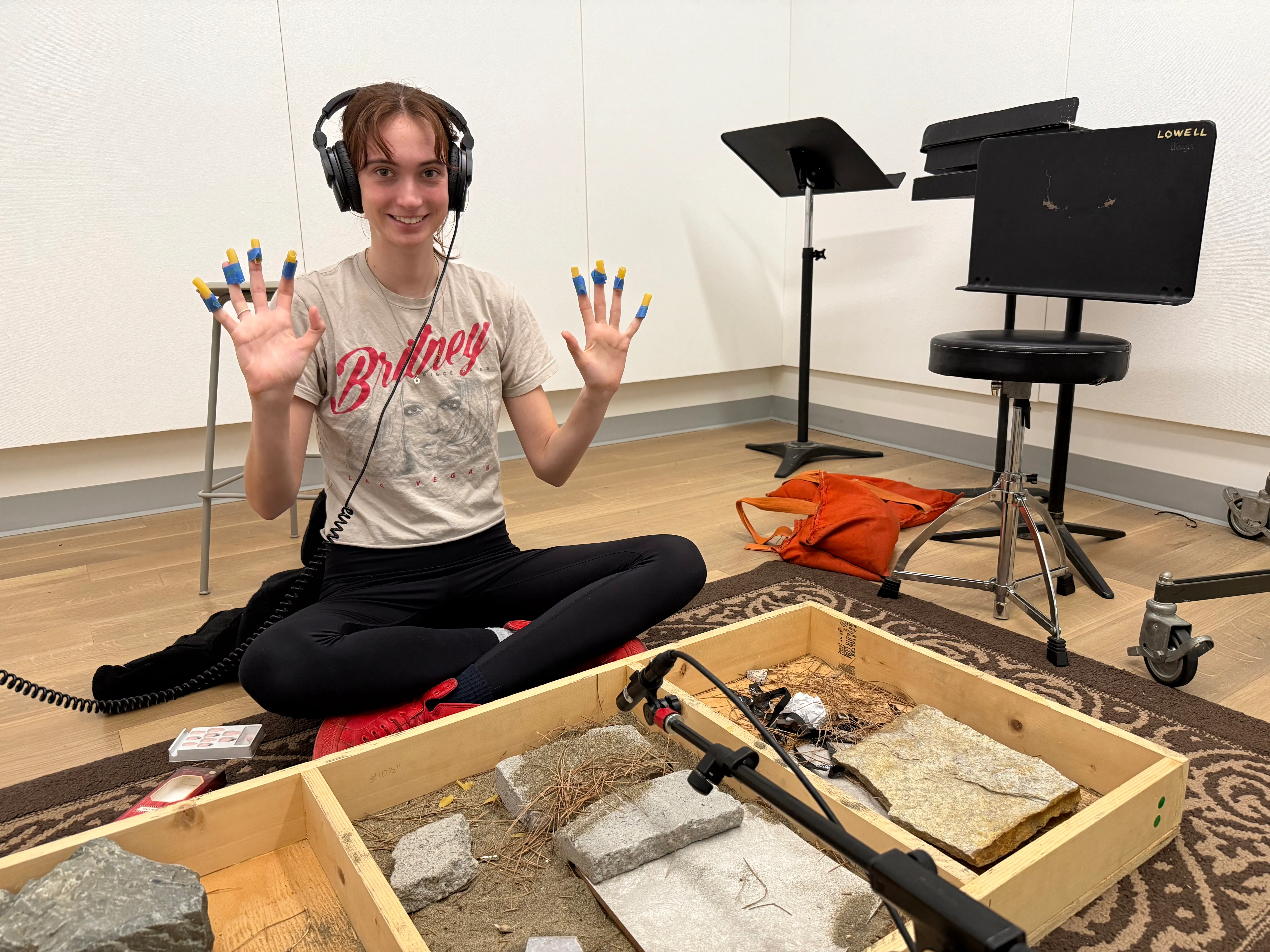 Madison with taped on macaroni in front of a microphone with several different materials.